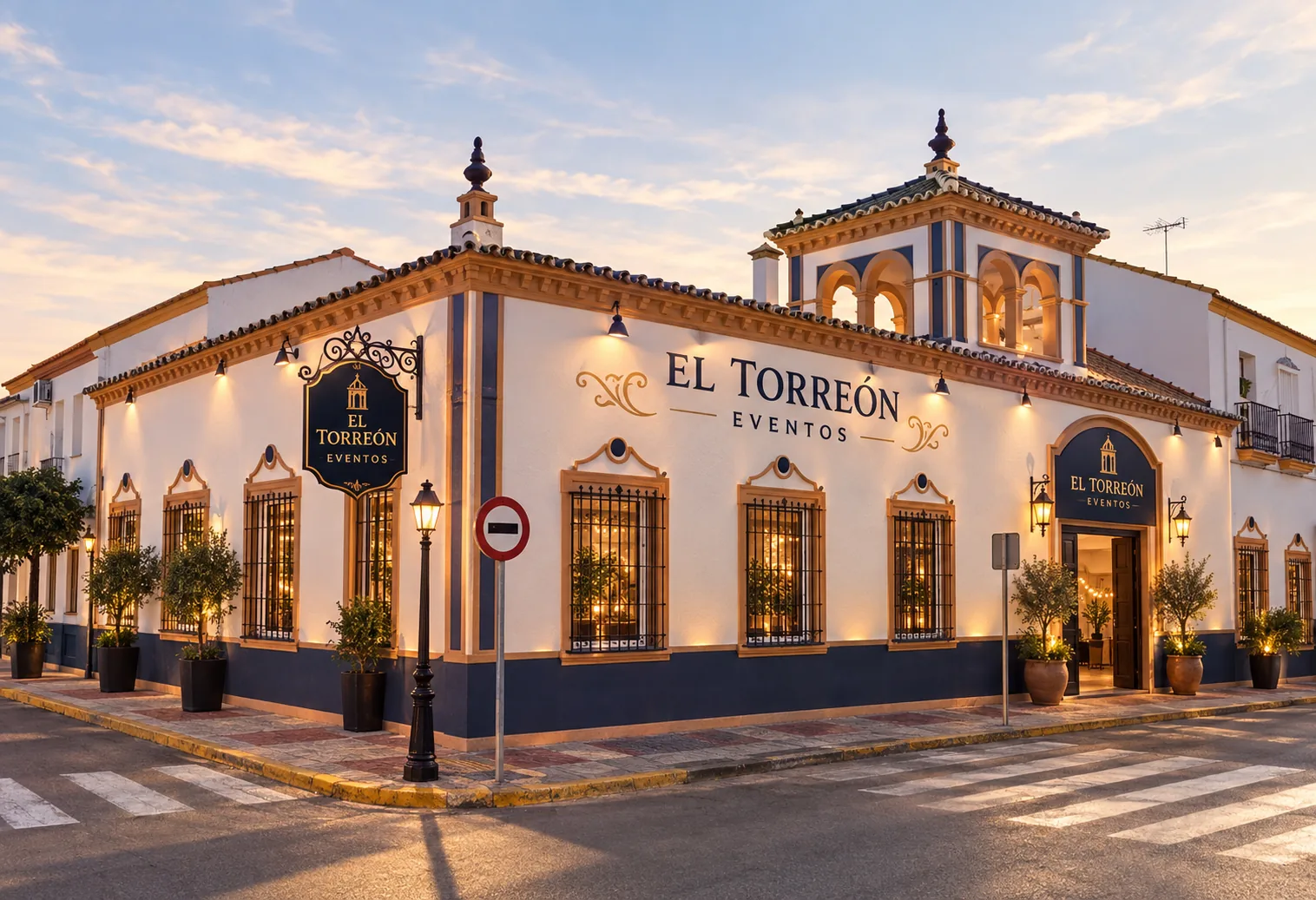 Fachada de El Torreón Eventos en Olivares al atardecer, con su torre de arcos, las molduras ocres y el zócalo azul